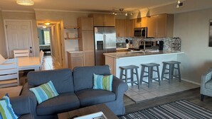 A modern kitchen with a central island, wooden cabinets, and stainless steel appliances. - Stunning 2BR/2BA Oceanfront Condo (Carolina Beach)