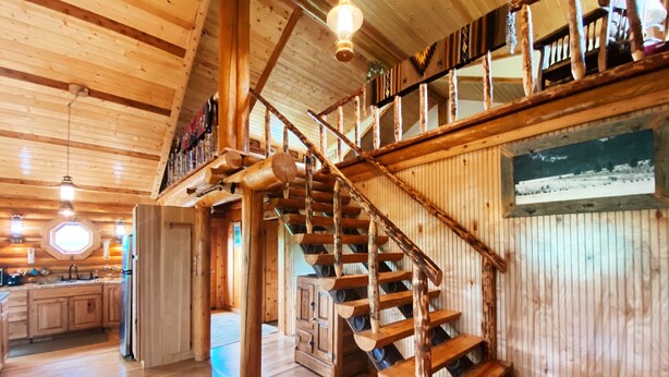 A wooden interior with a spiral staircase, wooden floors, and a kitchen area. - Perfect for Couples Or Families Up To 4 In Lovely Two Story Log Home  (Big Timber)