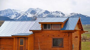 A log cabin with a metal roof, a front door, and a window. - Perfect for Couples Or Families Up To 4 In Lovely Two Story Log Home  (Big Timber)