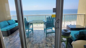 A balcony with a view of the ocean, featuring a table and chairs, a sofa, and a small table with a tire. - 12th Fl.Remodel 2021, East Wrap Ard View, 2br, Slps7; NEW one vrbo.com/2380847 (Orange Beach)