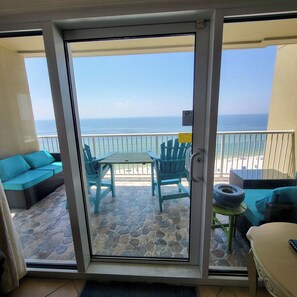 A balcony with a view of the ocean, featuring a table and chairs, a sofa, and a small table with a tire. - 12th Fl.Remodel 2021, East Wrap Ard View, 2br, Slps7; NEW one vrbo.com/2380847 (Orange Beach)