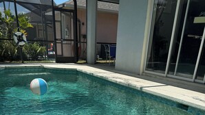 En swimmingpool med klart vand, en redningskrans og en blå og hvid strandbold.
