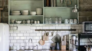 A kitchen with white tiled backsplash, wooden shelves, and a wooden countertop.