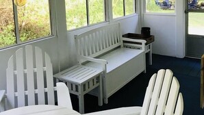A room with a white bench, two white chairs, a small table, and a hanging light fixture. - Harbor House Cottage located in the heart of Ephraim! (Ephraim)