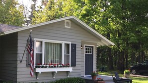 A small house with a front porch, a flag, and a bench. - Harbor House Cottage located in the heart of Ephraim! (Ephraim)