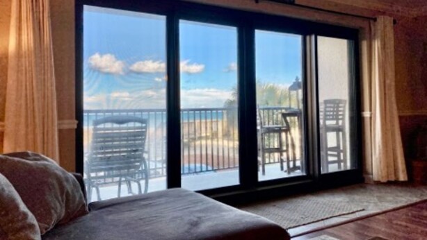 A room with a large sliding glass door leading to an outdoor patio with chairs and a table. - Fantastic place to make memories. Great ocean view condo for fun & “GOOD TIMES” (Pawleys Island)