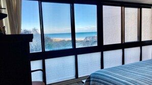 A bedroom with a large window, a bed, and a chair. - Fantastic place to make memories. Great ocean view condo for fun & “GOOD TIMES” (Pawleys Island)