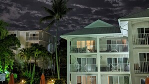 Un hotel con piscina, palmeras y un cielo iluminado por la luna.