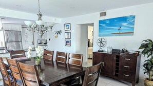 Una cocina moderna con comedor, que incluye una mesa de madera, sillas y una araña.