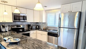 Una cocina moderna con gabinetes blancos, electrodomésticos de acero inoxidable y encimeras de granito.