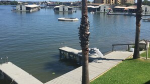 A marina with docked boats, a wooden dock, and a building with a flat roof in the background.