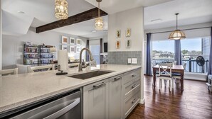 A modern kitchen with a large island, stainless steel appliances, and pendant lighting.