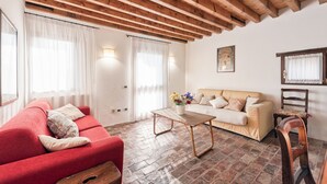 Una sala de estar con un sofá rojo, un sofá beige, una mesa de centro de madera y una silla de madera.