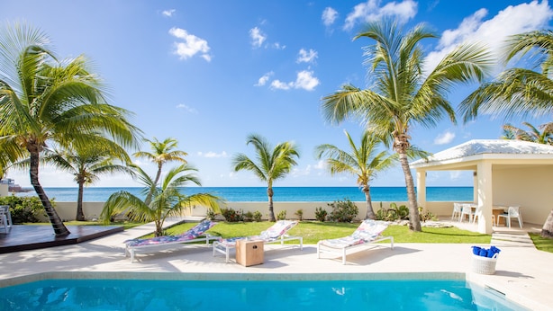 A pool area with lounge chairs and a view of the beach. - BEACHFRONT DESIGN VILLA (Beacon Hill)