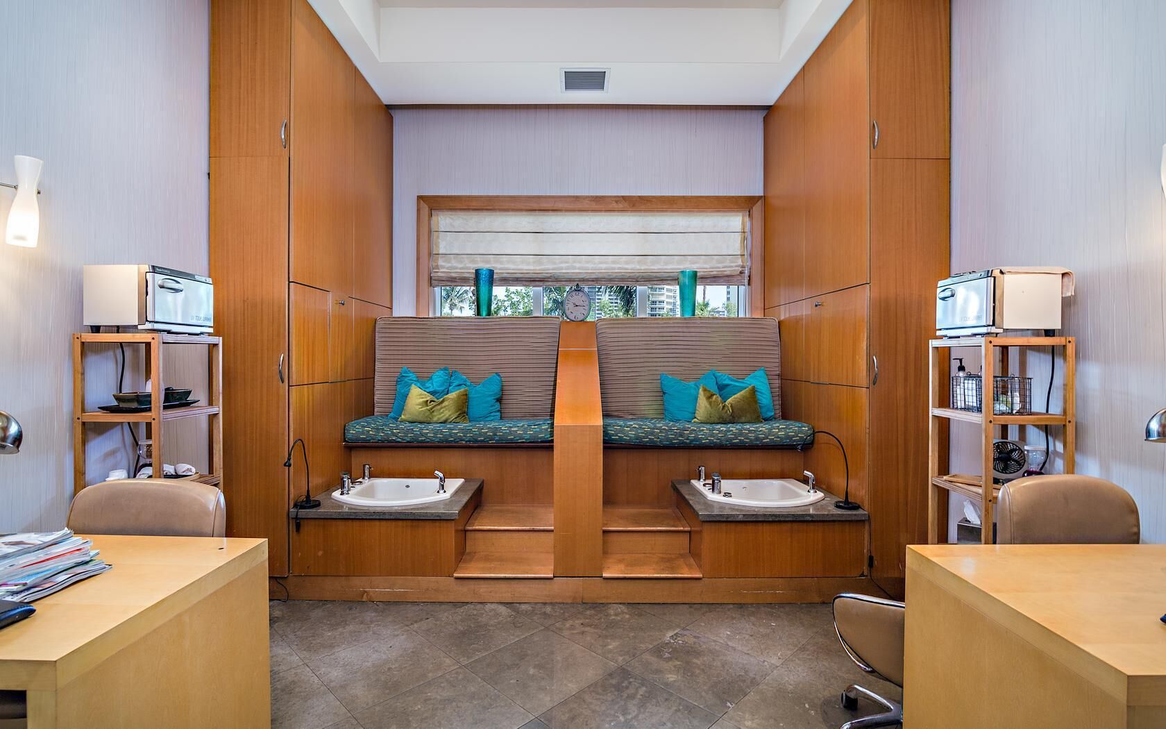 A compact, modern bathroom with two sinks, a window with blinds, and wooden cabinetry.