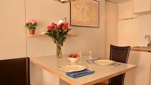 A dining area with a table set for two, a vase with flowers, and a map on the wall. - Lovely Modern Apartment - Walk to Champs Elysées - Best Area! (Paris)