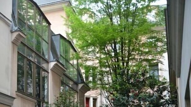 A courtyard with a central tree, surrounded by buildings with large windows and a stone pathway. - Lovely Modern Apartment - Walk to Champs Elysées - Best Area! (Paris)