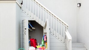 Eine Treppe führt zu einer Garage, in der sich ein pinker Kühler und eine weiße Tasche mit bunten Gegenständen befinden.