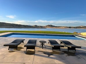Ein Schwimmbecken mit Liegestühlen und einem Tisch, umgeben von einer Betonplattform.