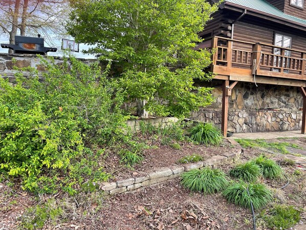 Una cabaña de madera con un muro de piedra y una terraza de madera.