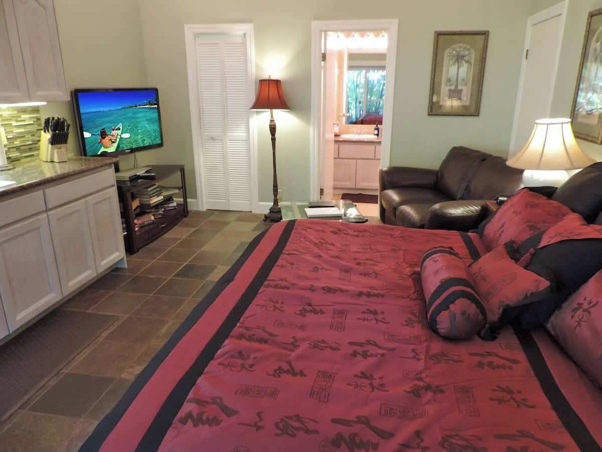 Un dormitorio con una cama, televisor, escritorio y una silla.