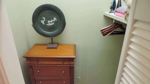 Ein kleines Badezimmer mit einem hölzernen Schminktisch, einem wandmontierten Spiegel und einem Regal mit gefalteten Handtüchern.