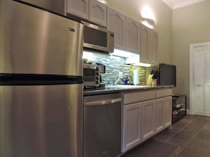 Una cocina con electrodomésticos de acero inoxidable, un microondas y un lavamanos.