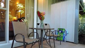 Eine Terrasse mit Tisch und Stühlen, ein Blumenstrauß in einer Vase und ein Kinderwagen.
