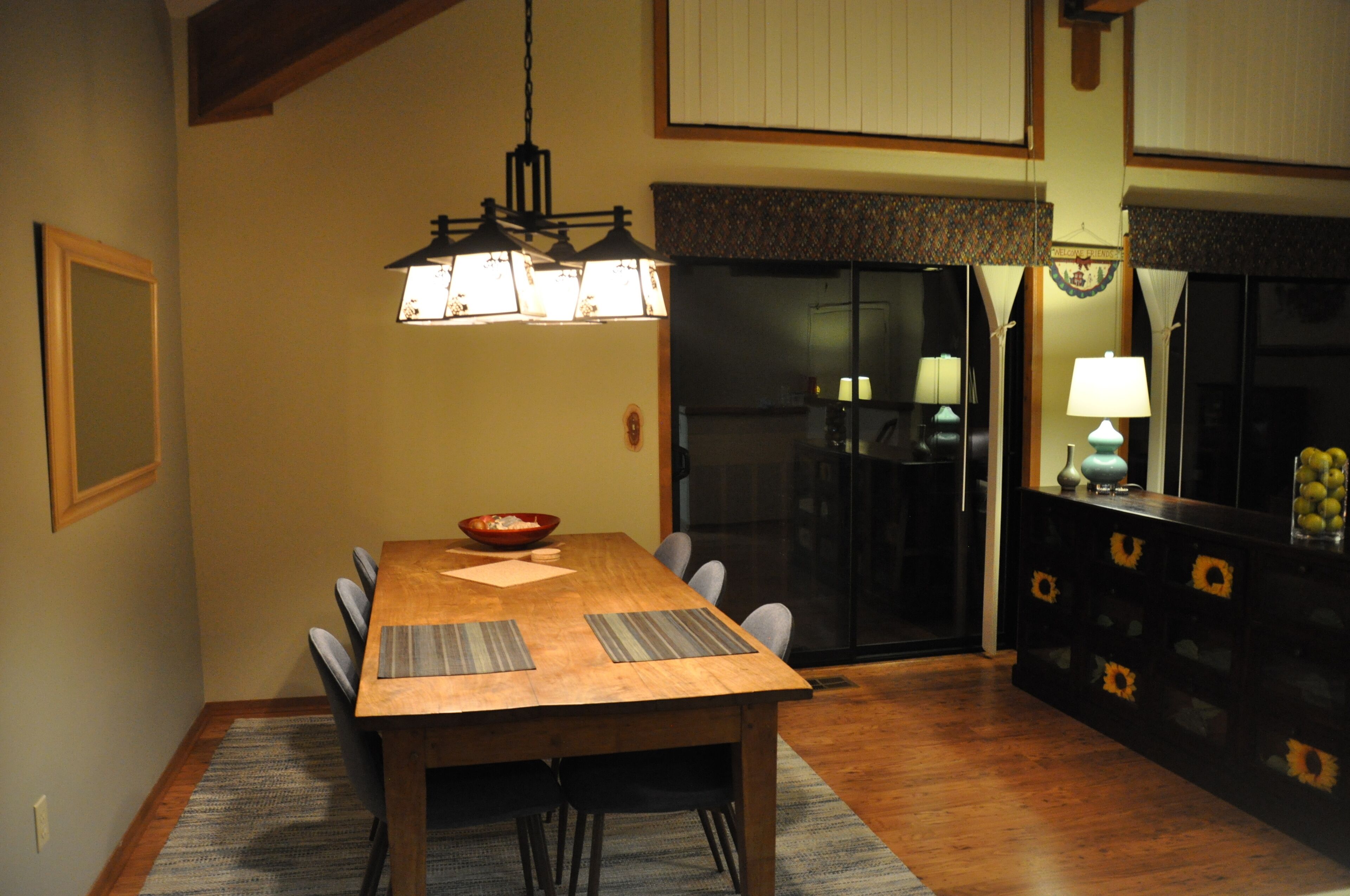 A dining area with a wooden table, chairs, and a hanging light fixture.