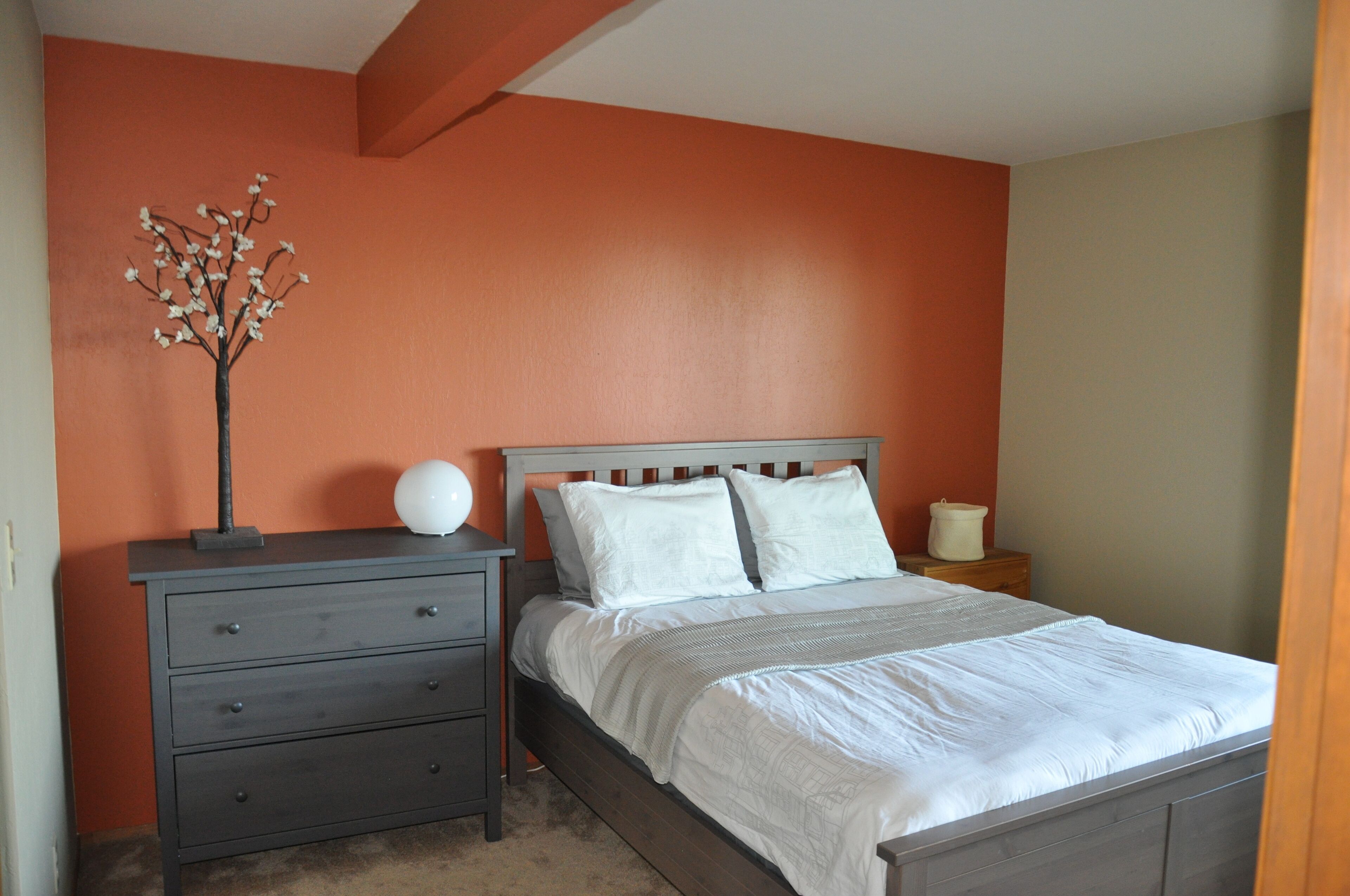 A bedroom with a bed, nightstands, a dresser, and a decorative tree.