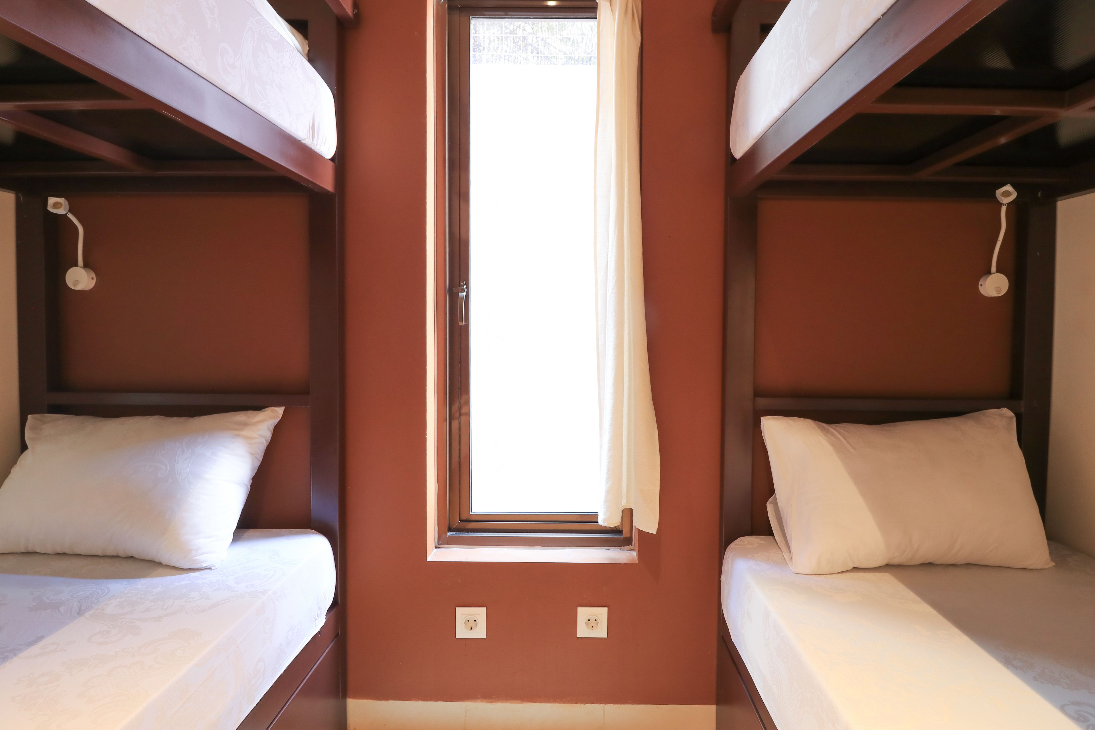 A room with two beds, a window, and a door.