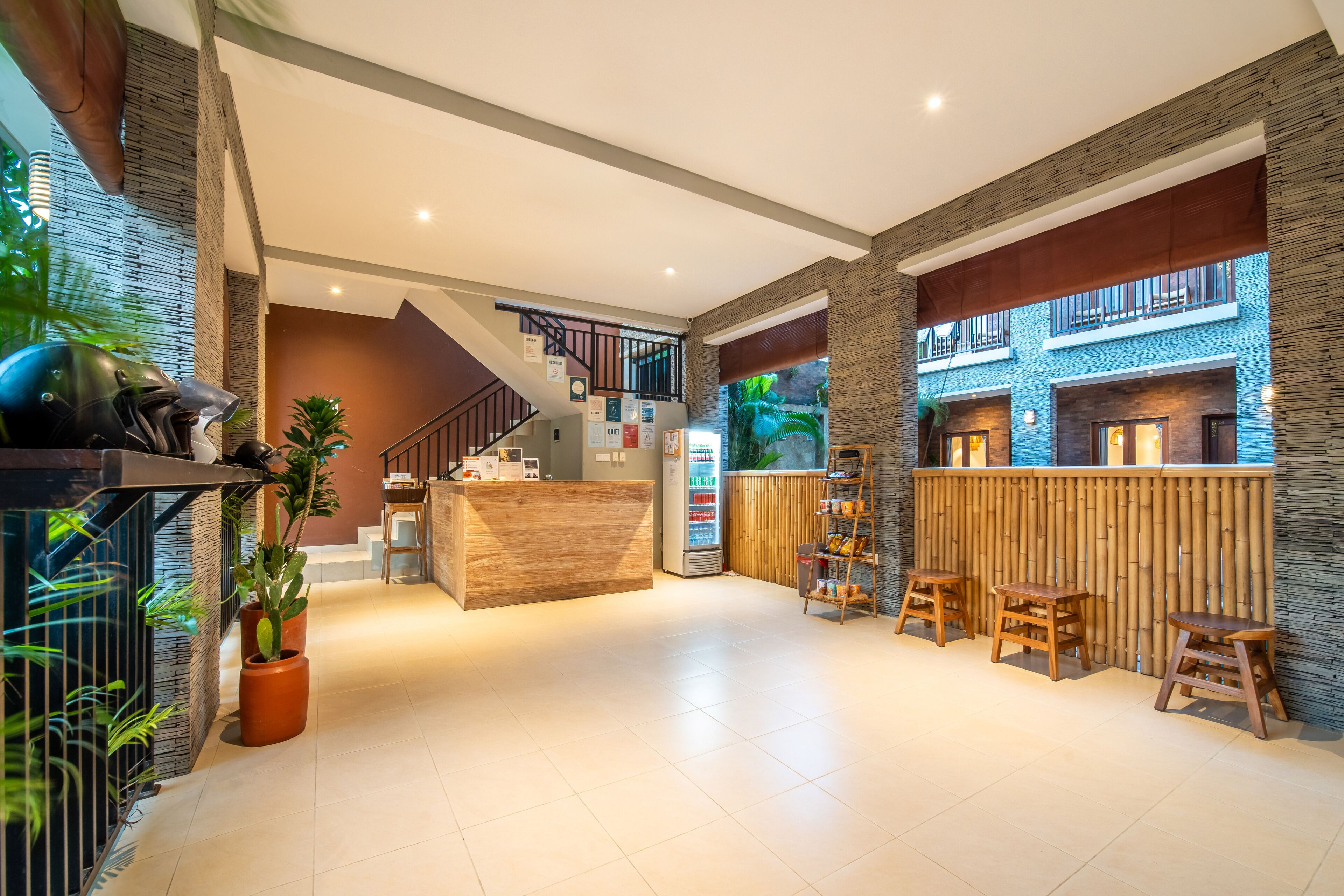 A modern lobby with a reception desk, seating area, staircase, and a vending machine.
