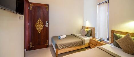 A hotel room with a wooden bed, a bedside table, a nightstand, a TV, and a window with curtains.