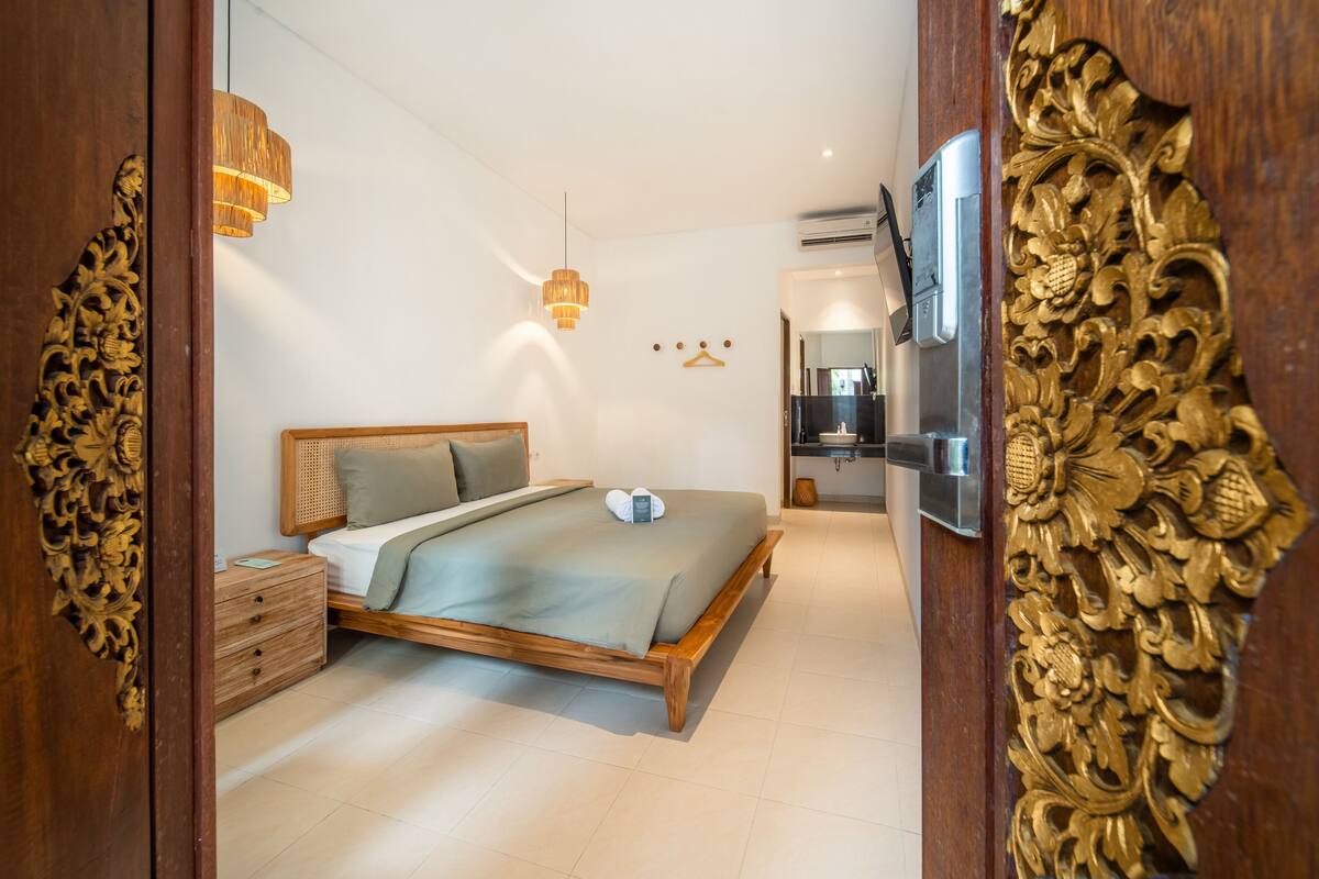 A bedroom with a bed, wooden nightstand, and a TV.