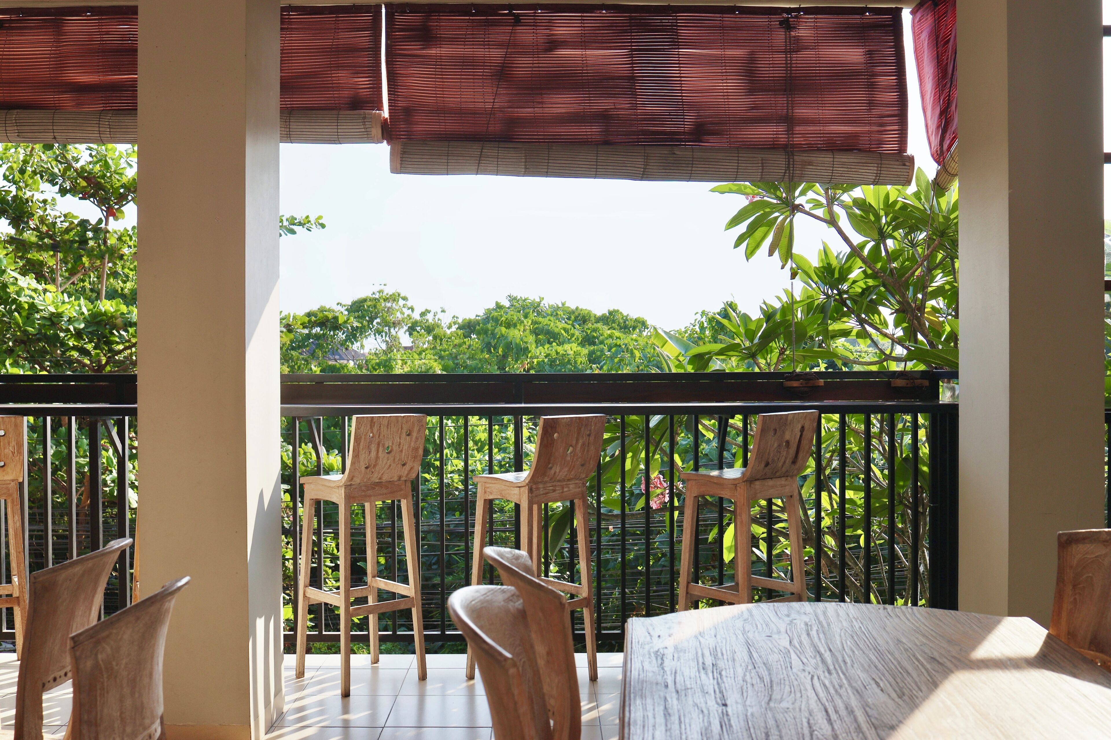 Un balcón con sillas y mesa de madera, con vistas a un jardín exuberante.