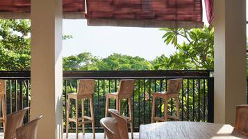 Un balcón con sillas y mesa de madera, con vistas a un jardín exuberante.