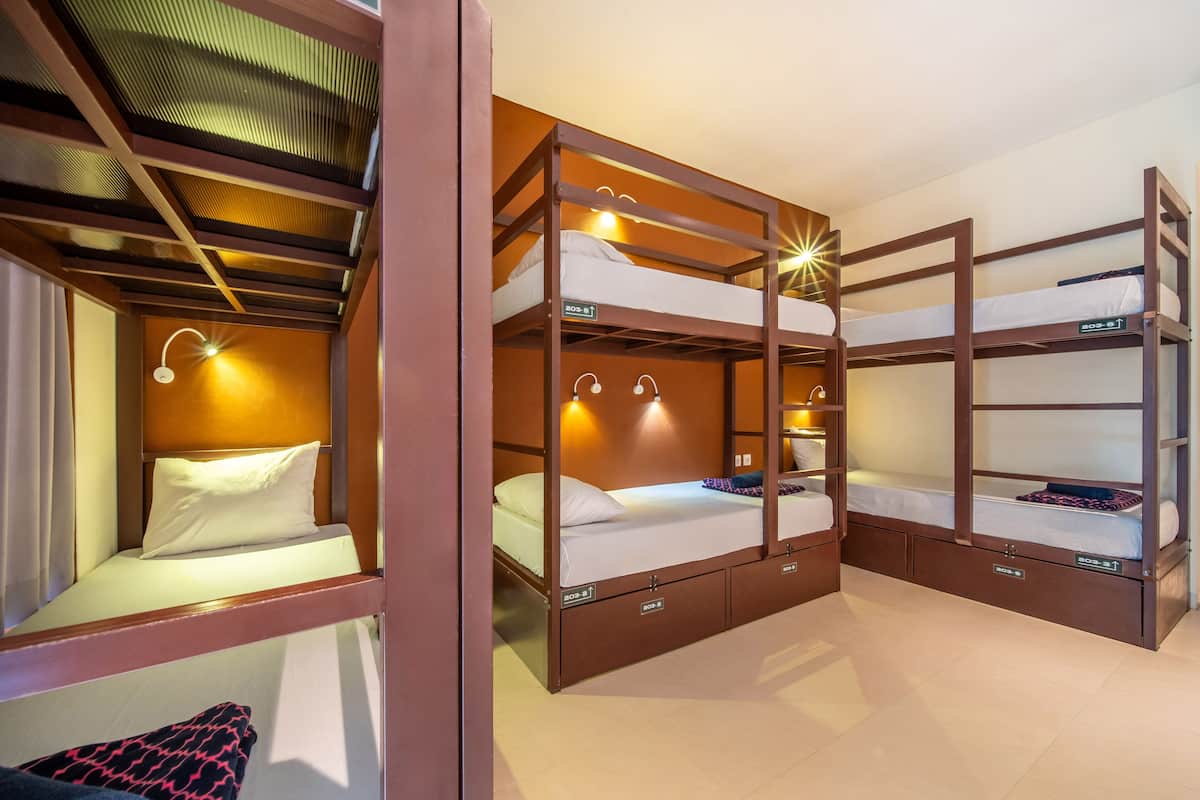 A bunk bed room with a wooden frame, built-in storage drawers, and wall-mounted lights.