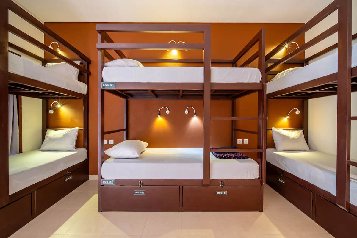 A bunk bed room with two beds, each with a pillow and a small nightstand. There are two wall-mounted reading lights.