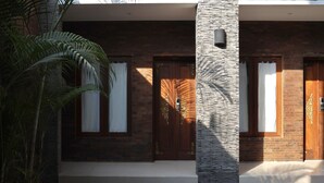 Um edifício moderno com duas portas de madeira, um pilar de pedra e um deck de madeira.