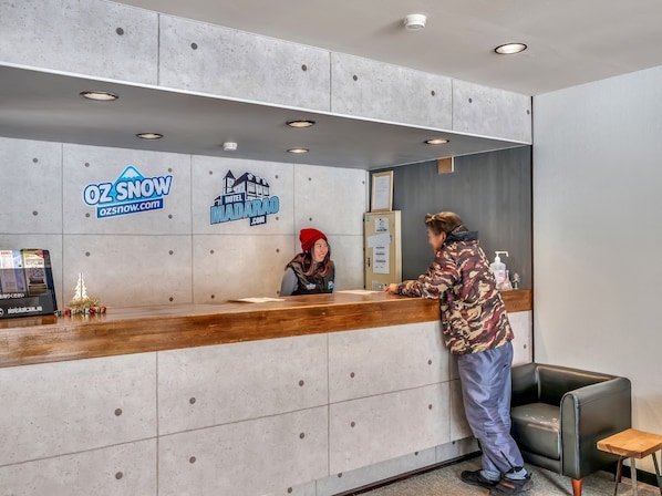 A hotel reception desk with a wooden counter, a small Christmas tree, and a sign for Hotel Madarao. - Apartments Madarao (Myoko)