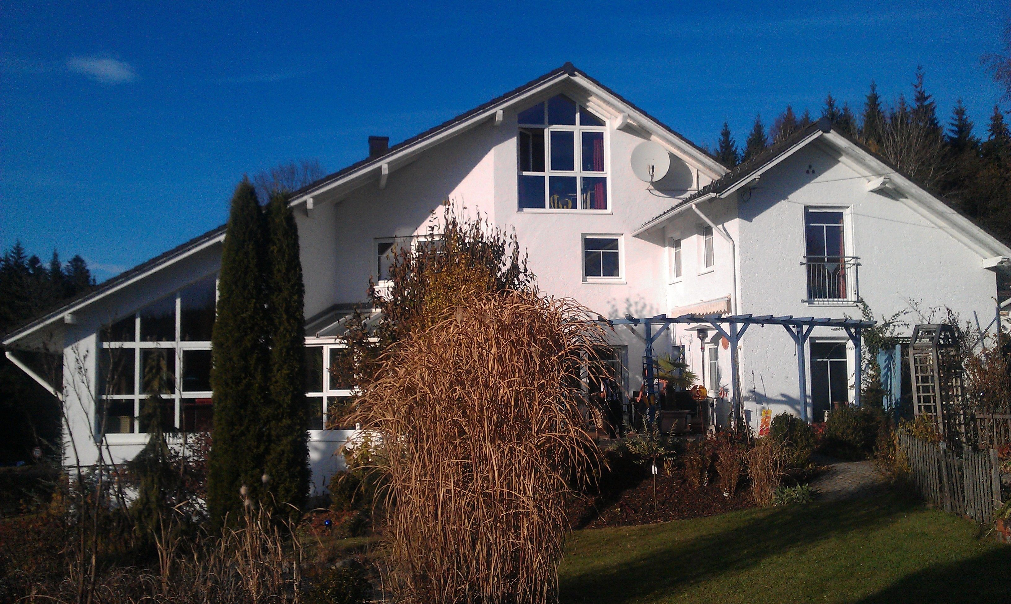 A two-story house with a large front porch, a satellite dish, and a garage.