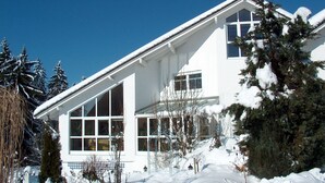 A two-story white house with large windows and a sloped roof covered in snow. - Wildnisresidenz am Nationalpark (Lindberg)