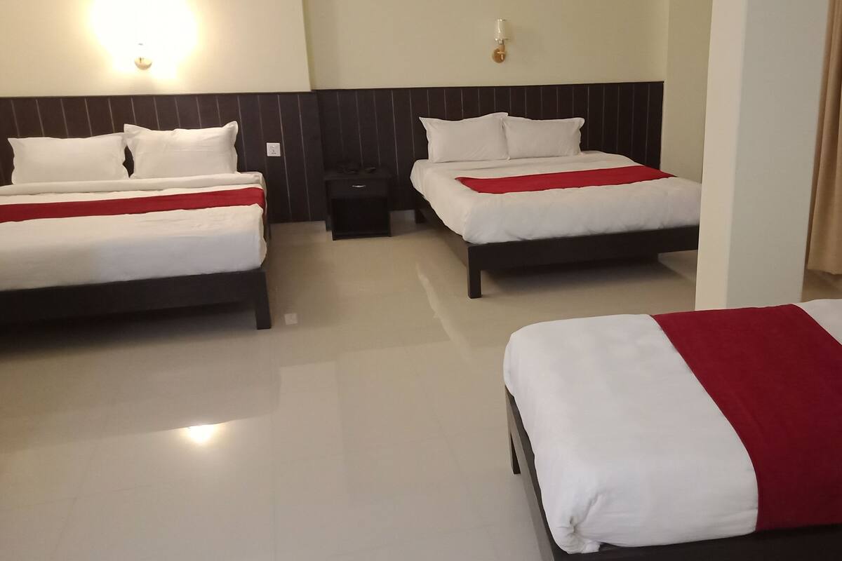 A hotel room with two beds, a nightstand, and a wall-mounted light fixture.