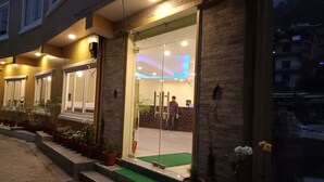 A hotel entrance with a glass door, potted plants, and a green carpet leading inside. - Hotel My Dream (Pokhara)