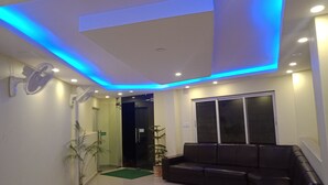 A modern interior with a black leather sofa, a glass door entrance, and a ceiling with blue LED lighting. - Hotel My Dream (Pokhara)