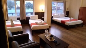 A hotel room with three beds, a sofa, a coffee table, and a view of the outside. - Hotel My Dream (Pokhara)
