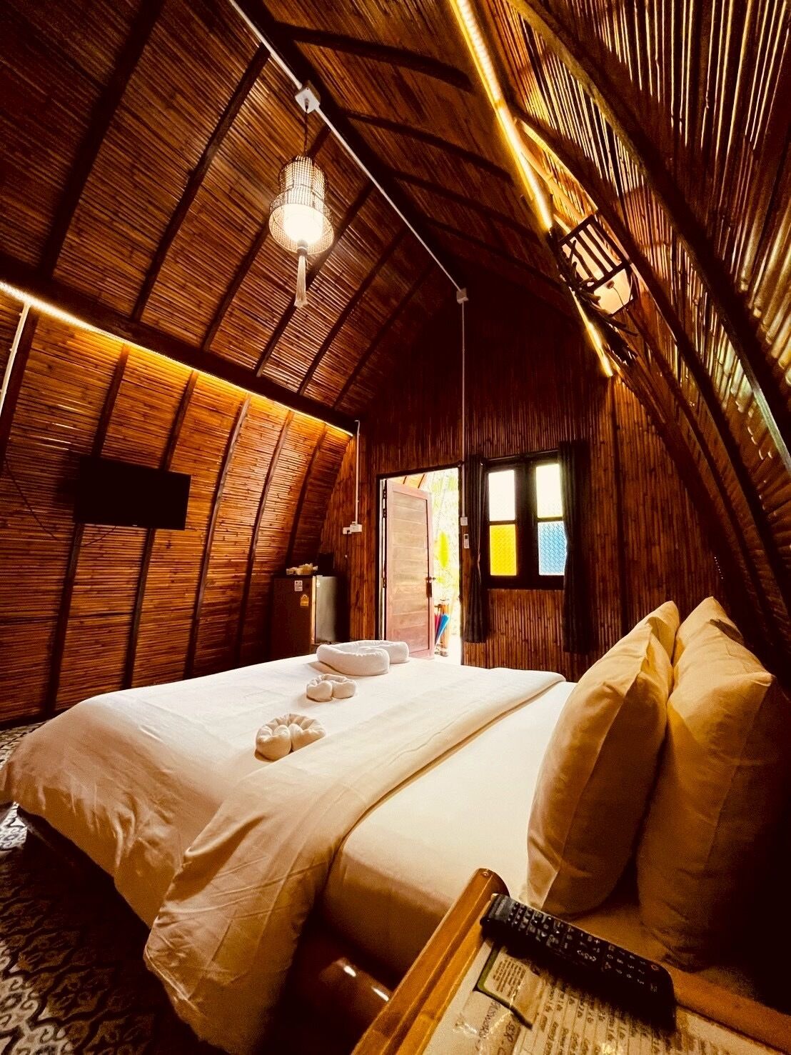 Ein gemütliches Schlafzimmer im Dachgeschoss mit einem großen Bett, einer Holzbalkendecke und einer Pendelleuchte.