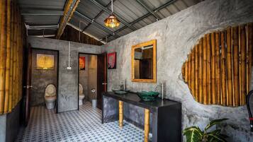 A bathroom with a bamboo wall, a sink with a green basin, and a mirror with a gold frame.