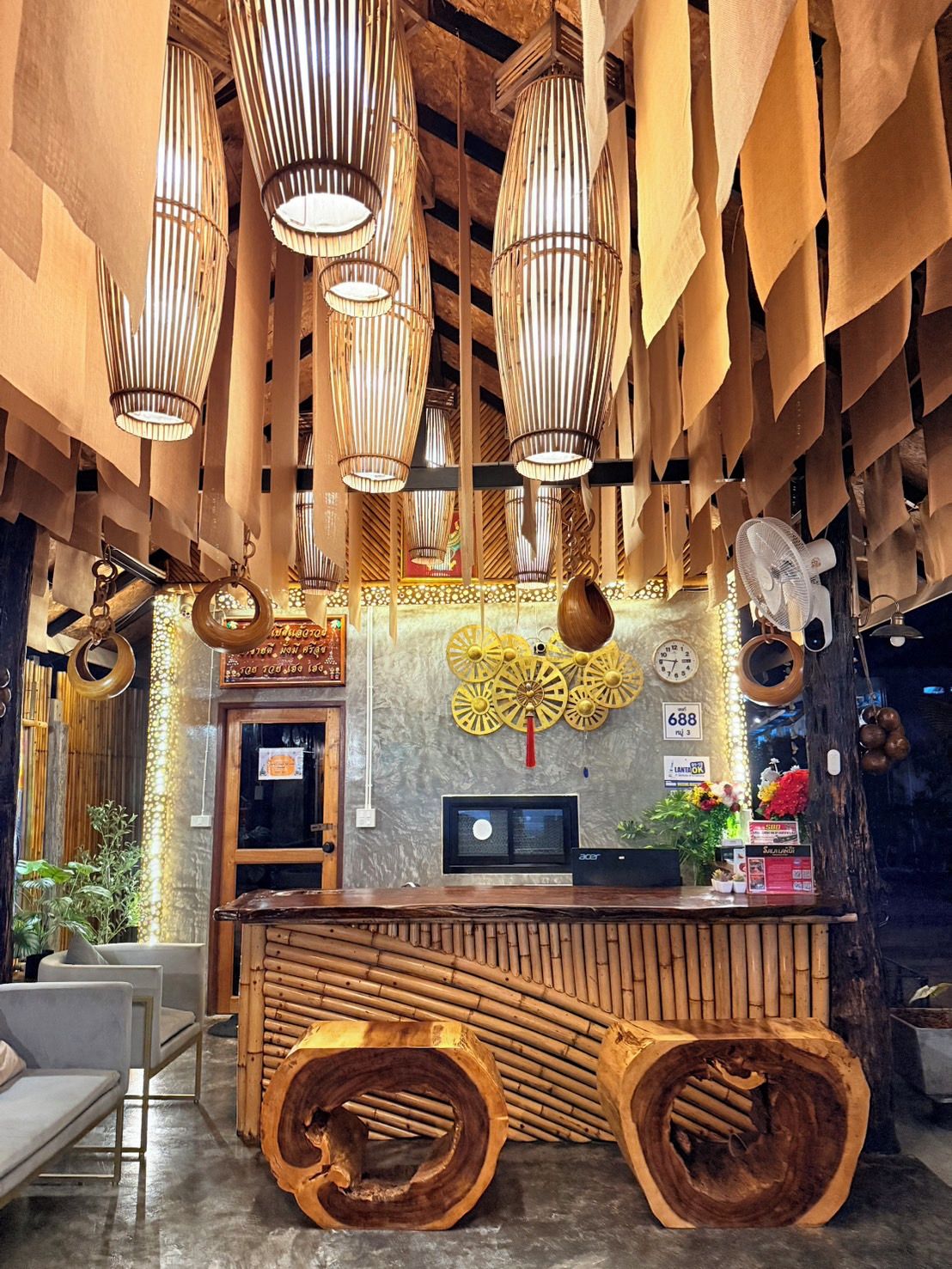 A reception area with a wooden reception desk, bamboo wall decor, and hanging bamboo lamps.