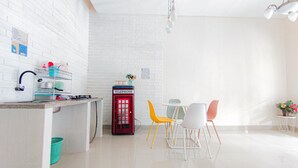 Een moderne keuken met een witte bakstenen muur, een rode telefooncel en een eethoek met kleurrijke stoelen.